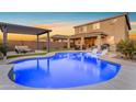 Beautiful backyard pool featuring lounge chairs in the water and a shaded outdoor dining area at 25582 S 224Th Way, Queen Creek, AZ 85142