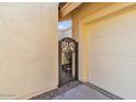 Close up of a garage featuring a decorative metal gate, stucco wall, and desert landscaping at 2630 N El Dorado Pl, Chandler, AZ 85224