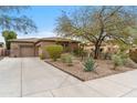 Beautiful single-story home featuring desert landscaping, a three-car garage, and a paved driveway at 9869 E Davenport Dr, Scottsdale, AZ 85260