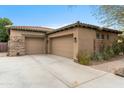 Spacious three-car garage with stone accents and a concrete driveway at 9869 E Davenport Dr, Scottsdale, AZ 85260