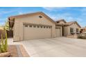 View of the house showing three car garage with desert landscaping at 11123 E Olla Ave, Mesa, AZ 85212