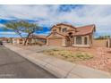Two-story home with a tile roof, two-car garage, desert landscaping and mature trees at 12574 W Desert Rose Rd, Avondale, AZ 85392