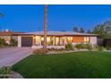 Charming single-story home with a well-manicured lawn, desert landscaping, and modern design elements at 1825 N Granite Reef Rd, Scottsdale, AZ 85257