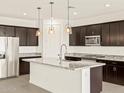 Modern kitchen featuring dark wood cabinets, stainless steel appliances, and a spacious island with granite countertops at 24612 W Grenadine Rd, Buckeye, AZ 85326