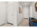 Bright hallway featuring neutral tile floors, white doors, and a stylish blue console table at 26947 W Adam Ave, Buckeye, AZ 85396