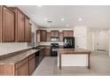 Well-lit kitchen featuring dark cabinets, black appliances, and a functional center island at 5108 N 191St Dr, Litchfield Park, AZ 85340