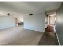 A bright, carpeted living room with neutral walls and a ceiling fan, ready for personalization at 9059 N Arroya Grande Dr, Phoenix, AZ 85028