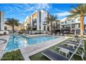 Stunning community pool surrounded by lounge chairs, palm trees, and modern townhomes against a bright blue sky at 1717 E Morten Ave # 2, Phoenix, AZ 85020