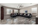 Spacious living room featuring marble floors, a ceiling fan, and a comfortable sectional sofa at 25420 W Park Ave, Buckeye, AZ 85326