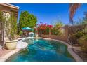 Inviting backyard pool surrounded by lush greenery and red bougainvillea, perfect for relaxation and outdoor enjoyment at 26815 N 65Th Ave, Phoenix, AZ 85083