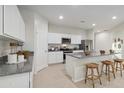 Modern kitchen with white cabinets, stainless steel appliances, and a granite-topped island with seating at 36020 W San Ildefanso Ave, Maricopa, AZ 85138