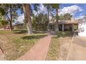 View of a brick walkway extending to a well-maintained front yard with mature trees, and cozy home at 6854 W Wagoner Rd, Glendale, AZ 85308