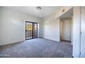 A bright bedroom featuring neutral carpet and a glass sliding door to a private balcony at 3434 E Baseline Rd # 213, Phoenix, AZ 85042
