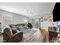 Spacious living room with a large sectional sofa, a ceiling fan, hardwood floors and sliding glass door access at 37340 W Merced St, Maricopa, AZ 85138