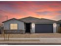 Charming single-story home with a gray exterior, a gray tiled roof, and a brick driveway at 4029 S 176Th Dr, Goodyear, AZ 85338