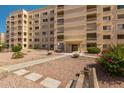 Exterior shot of a tan building showcasing its architectural facade with balconies and walkways and landscaped entrance at 7920 E Camelback Rd # 408, Scottsdale, AZ 85251