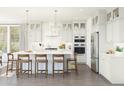 Bright, modern kitchen with white cabinets, stainless steel appliances, an island with seating, and elegant pendant lighting at 7982 W Griswold Rd, Peoria, AZ 85345