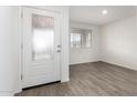 Bright entryway featuring wood-look flooring, neutral paint, and a front door with decorative glass panel at 8552 S 258Th Dr, Buckeye, AZ 85326