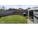 Spacious backyard featuring a well-maintained lawn, block wall fencing, and outdoor grill at 1409 E Apollo Rd, Phoenix, AZ 85042