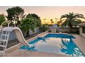 Backyard pool featuring a slide, palm trees, and privacy walls ideal for relaxation and summer fun at 2107 E Inca St, Mesa, AZ 85213