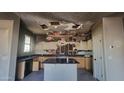 Kitchen showing damage to walls and ceilings with kitchen island and light wood cabinets at 2834 S Brett St, Gilbert, AZ 85295