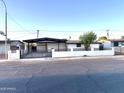 Charming single-story home featuring a covered carport and modern horizontal slat privacy fence at 7754 W Mitchell Dr, Phoenix, AZ 85033