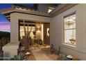 Inviting covered front porch with comfortable seating, desert landscaping, and a stylish entrance door creating a warm welcome at 11617 E Raintree Dr, Scottsdale, AZ 85255