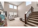 Bright living room with soaring ceilings, large windows, plush seating, and staircase at 17474 W Straight Arrow Ln, Surprise, AZ 85387