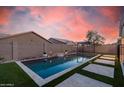 Inviting backyard pool with water feature, travertine deck, and lush artificial turf at 21255 W Ashland Ave, Buckeye, AZ 85396