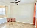 Bright living room with tan tile flooring, accent pillows, and a ceiling fan at 2315 E Pecan Rd, Phoenix, AZ 85040