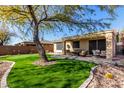 Lush backyard features artificial turf, a putting green, mature trees, and a cozy seating area with a fire pit at 2951 W Plum Hollow Dr, Anthem, AZ 85086