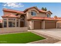 A view of the home's front exterior features a green lawn, a desert-style gravel bed, and a three-car garage at 4129 E Nighthawk Way, Phoenix, AZ 85048