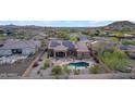 A high-angle view of a house with solar panels, a pool and patio surrounded by desert landscaping at 10931 S Santa Columbia Dr, Goodyear, AZ 85338