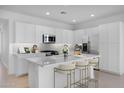 Bright kitchen with white cabinets, stainless steel appliances, quartz counters, and a spacious center island with bar seating at 14777 W Soft Wind Dr, Surprise, AZ 85387