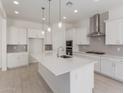 Bright kitchen features a large island, white cabinets, stainless steel appliances, and stylish pendant lighting at 21640 E Roundup Way, Queen Creek, AZ 85142