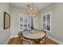 Bright dining room with a round wood table, stylish chandelier, and plantation shutters on the windows at 3812 E Parkside Ln, Phoenix, AZ 85050