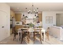 Open-concept dining area with a stylish chandelier, view to the kitchen, and seating for six at 7993 W Griswold Rd, Peoria, AZ 85345