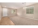 Spacious living room with carpet flooring, ample natural light, and a modern chandelier at 11128 E Segura Ave, Mesa, AZ 85212