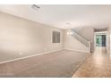 Open-concept living room with tiled entry, carpet, and a view of the staircase at 11128 E Segura Ave, Mesa, AZ 85212