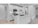 Bright, modern kitchen features white cabinetry, stainless steel appliances, and a sleek island at 16778 W Yucatan Dr, Surprise, AZ 85378