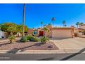 Charming single-story home featuring a spacious two car garage, mature landscaping, and a red double door entrance at 26401 S Brentwood Dr, Sun Lakes, AZ 85248