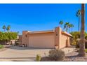 Two car garage with light peach paint and desert landscaping with several palm trees in the front yard at 26401 S Brentwood Dr, Sun Lakes, AZ 85248