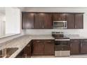 Modern kitchen with stainless steel appliances, granite countertops, and dark wood cabinets at 5073 S 251St Dr, Buckeye, AZ 85326