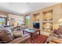 Cozy living room features built-in shelving with a red area rug beneath a wooden table and brown leather furniture at 8212 E Masters Rd, Gold Canyon, AZ 85118