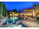 A backyard pool and spa are illuminated at night, with an outdoor dining area and manicured landscaping at 9547 N 55Th St, Paradise Valley, AZ 85253