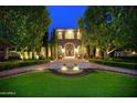 Front exterior featuring a stone facade, fountain, manicured landscaping, and illuminated trees at 9547 N 55Th St, Paradise Valley, AZ 85253