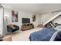 Comfortable living room features neutral tile, cozy chair, TV, artwork, and stairs at 13204 N 3Rd Way, Phoenix, AZ 85022