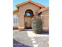 Charming home's front entrance has an arched doorway and a desert landscaped yard with rock cover at 14460 N 100Th Way, Scottsdale, AZ 85260