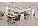 Open-concept dining area with a modern table, adjacent to a kitchen island with bar stools, creating an inviting space at 1724 E Bridgeport Pkwy, Gilbert, AZ 85295