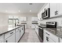 Modern kitchen with stainless steel appliances, granite countertops, and white cabinets at 35621 W San Alvarez Ave, Maricopa, AZ 85138